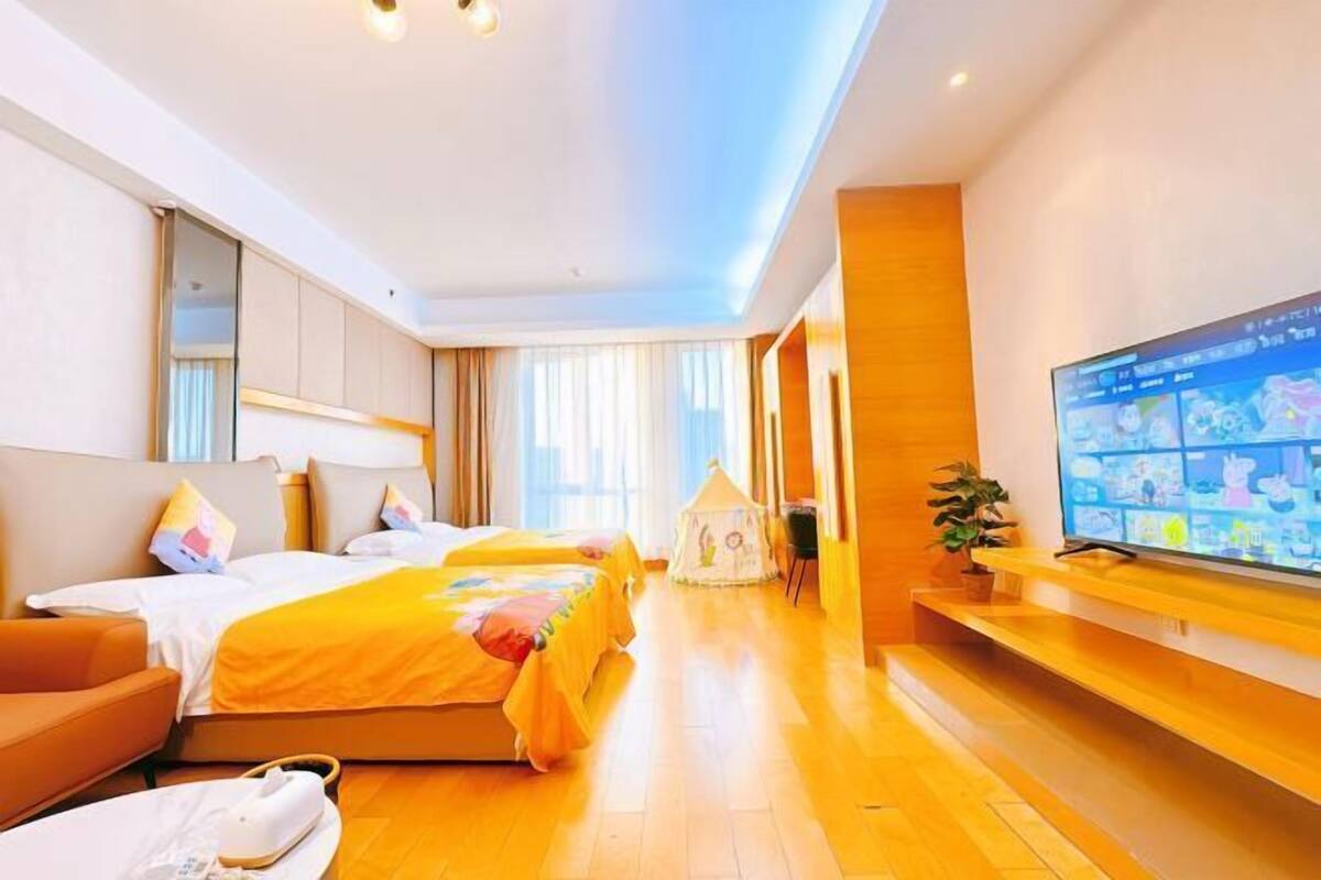 Una camera d'albergo con due letti, una televisione, una panca in legno e un tavolino.