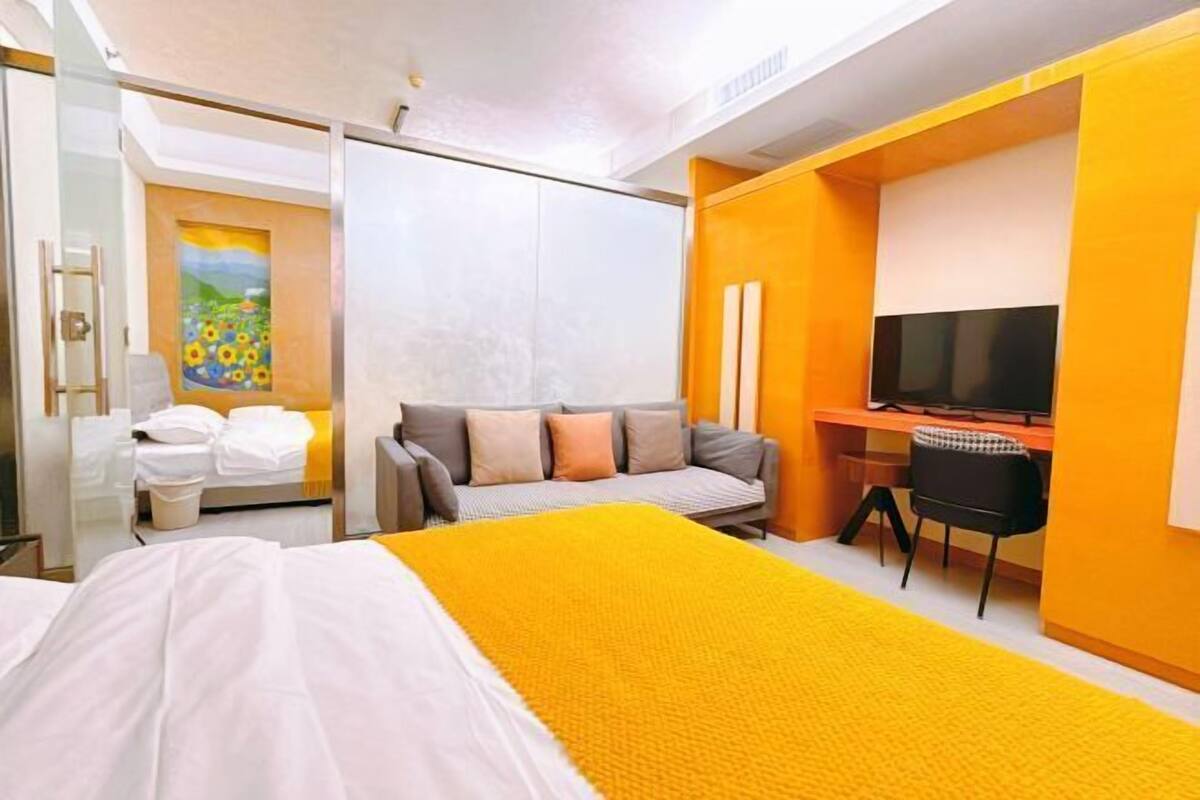 Una camera d'albergo con un letto, una scrivania, una sedia, una TV e un quadro appeso al muro.
