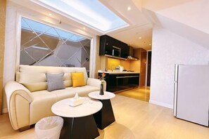 A modern living room with a sofa, coffee table, and a view of the kitchen. - Yijia Apartment (Beijing Workers' Stadium) (Beijing)
