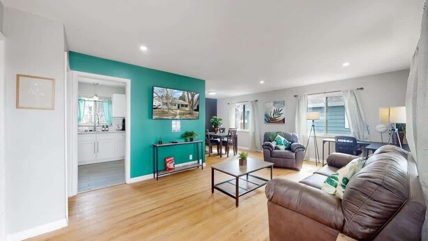 A modern living room with a brown leather sofa, a coffee table, and a teal accent wall. - Large Family Retreat in Quiet Denver Spot (Denver)
