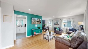 A modern living room with a brown leather sofa, a coffee table, and a teal accent wall. - Large Family Retreat in Quiet Denver Spot (Denver)