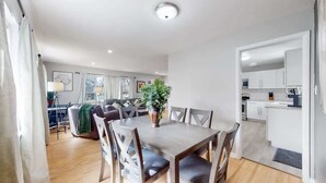 A modern living room with a dining table and chairs, a sofa, a coffee table, and a potted plant. - Large Family Retreat in Quiet Denver Spot (Denver)