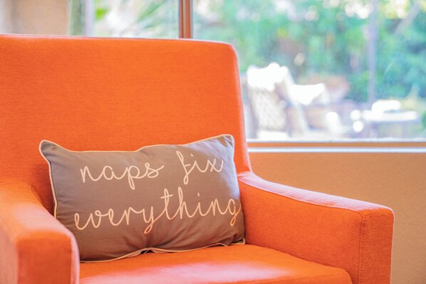A chair with an orange cushion and a pillow with the text 'naps for everything' on it. - Scottsdale Treasure: Private Pool and Tranquil Yard Retreat! (Scottsdale)