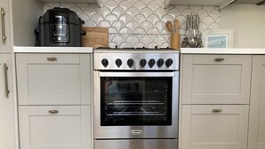 Eine Küche mit eingebautem Backofen, Edelstahl-Schränken und einer gefliesten Spritzschutzwand.