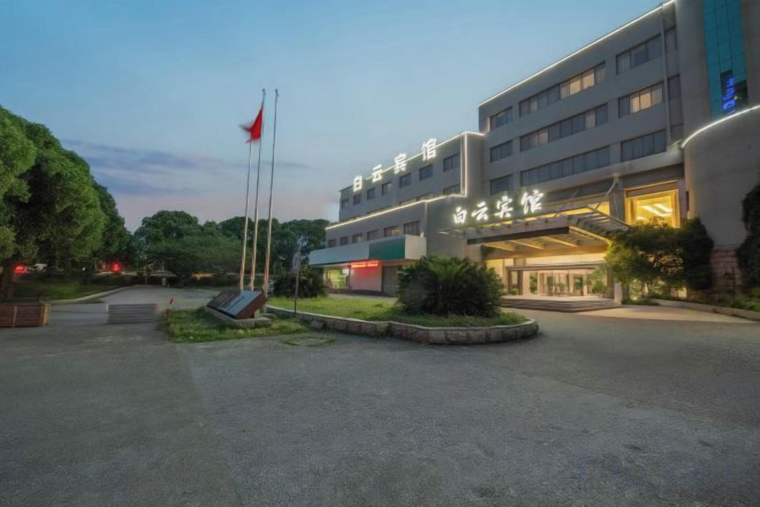 A hotel with a modern facade, a flagpole, and a well-maintained garden area.