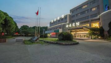 A hotel with a modern facade, a flagpole, and a well-maintained garden area.