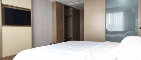 Una habitación de hotel con cama, televisión montada en la pared y armario corredero.
