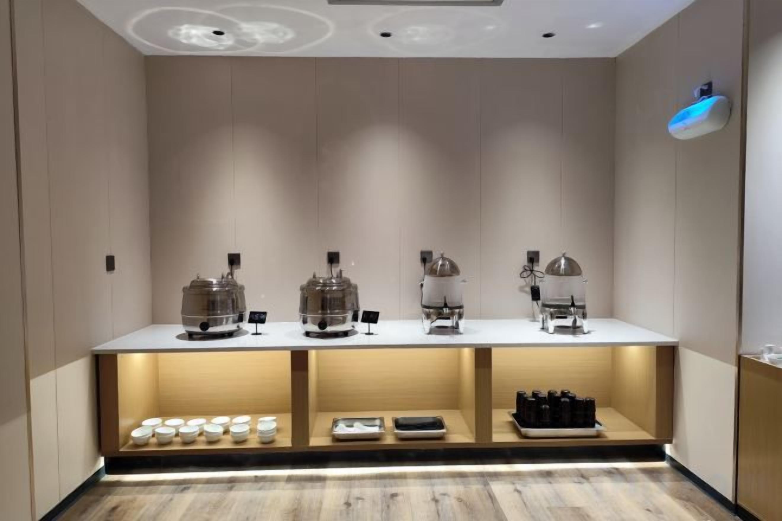 Zona de bar moderna con una barra que exhibe cafeteras y una variedad de bebidas.