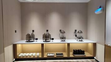 Zona de bar moderna con una barra que exhibe cafeteras y una variedad de bebidas.