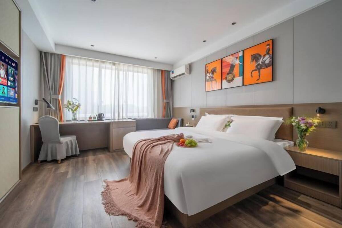 Una habitación de hotel moderna con una cama grande, un escritorio y un ventanal con cortinas.
