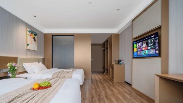 Una habitación de hotel con dos camas, televisión, escritorio y armario.