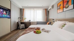 Habitación de hotel con cama, escritorio, silla, televisor y ventana con cortinas.