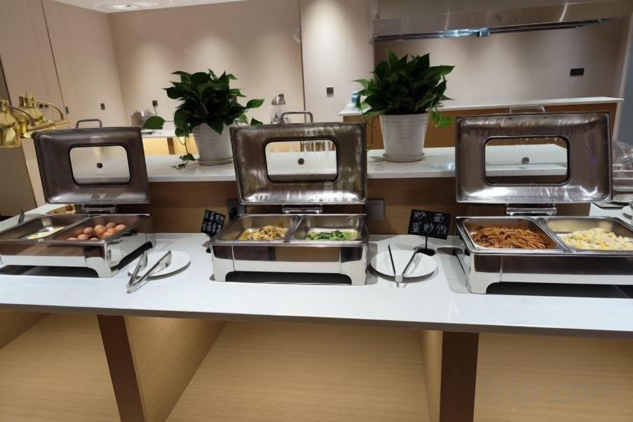 A buffet setup with multiple food stations, including trays of eggs, salads, and other dishes, in a modern hotel setting.