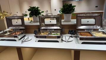 A buffet setup with multiple food stations, including trays of eggs, salads, and other dishes, in a modern hotel setting.