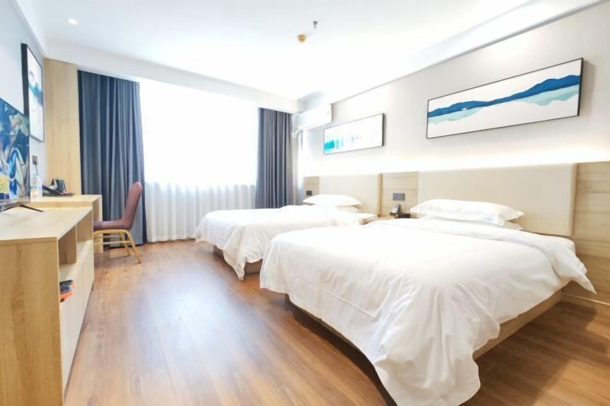 Habitación de hotel con dos camas, un escritorio y una silla.