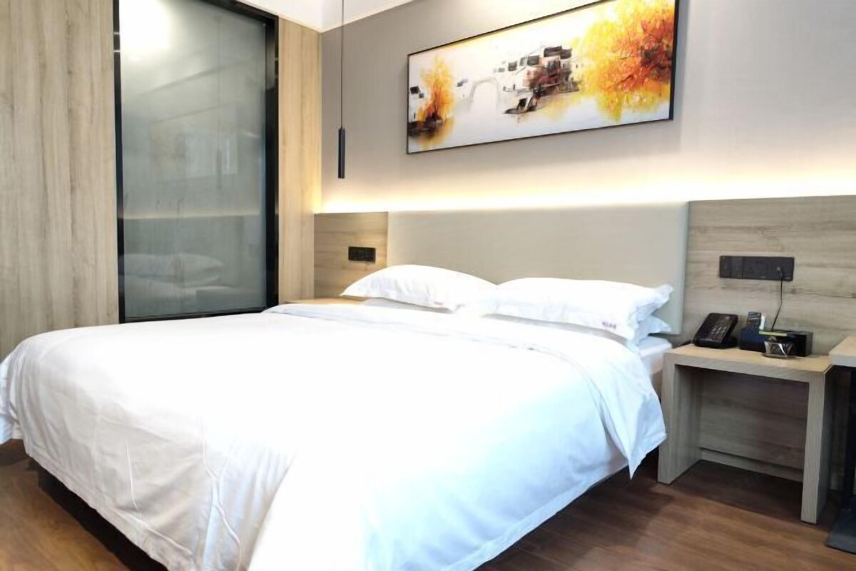 Una habitación de hotel con una cama, una mesita de noche con un teléfono y una obra de arte colgada en la pared.