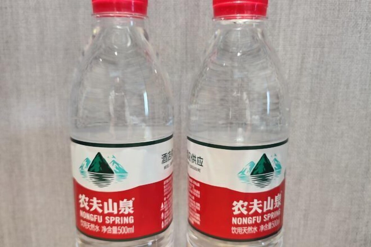 Dos botellas de plástico transparente con tapones rojos, etiquetadas como 