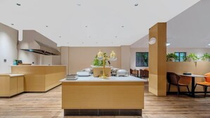 Una cocina moderna con una isla central, suelo de madera y un comedor con sillas y mesas.