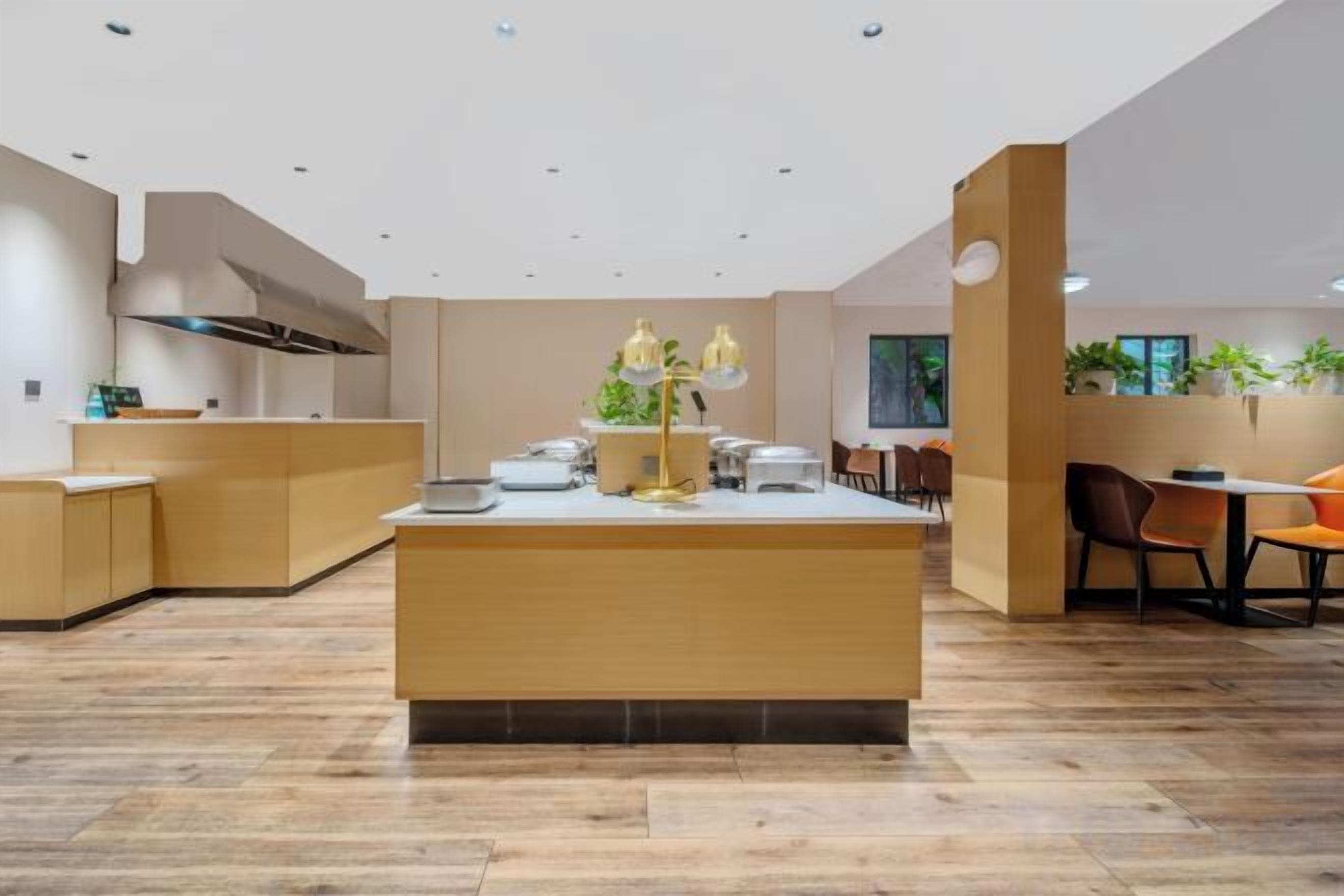 Una cocina moderna con una isla central, suelo de madera y un comedor con sillas y mesas.
