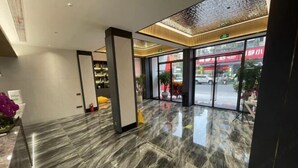 A modern lobby with a marble floor, large pillars, and a view of the street outside.