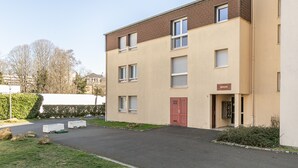 Un edifici residencial de diversos pisos amb façana color beix, una porta vermella i un rètol que indica el nom "MEREPOE".