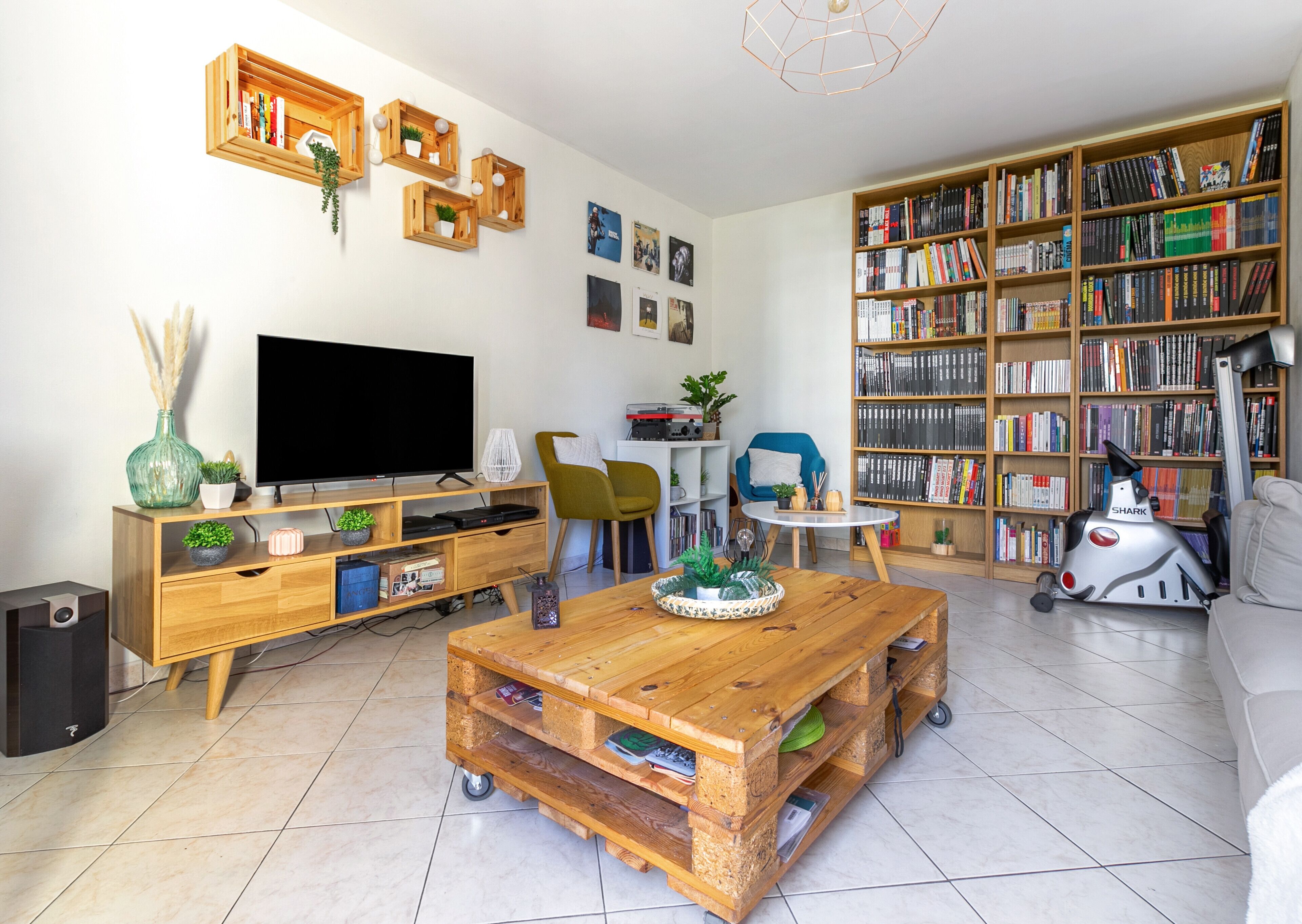 A living room with a TV, wooden furniture, a bookshelf, and a scooter.