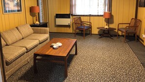A room with a sofa, two chairs, a small table, a radiator, and a window with curtains. - The Meadow Cabin at Horn Cabins in Manns Choice PA (Manns Choice)