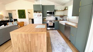 Een moderne keuken met een centraal eiland, roestvrijstalen apparatuur en licht houten vloeren.