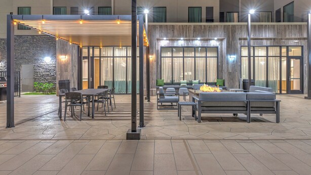 An outdoor patio with seating, a fire feature, and a covered area with string lights. - Staybridge Suites Port Arthur by IHG (Port Arthur)