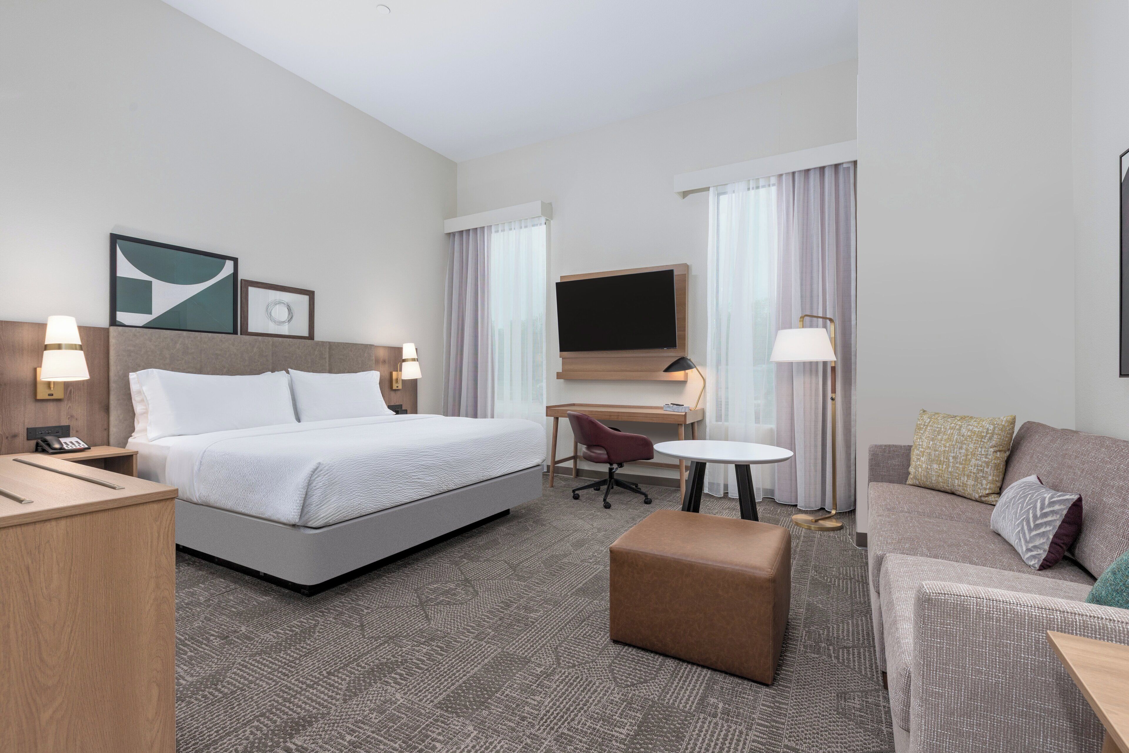 A hotel room with a bed, desk, chair, and a sofa.