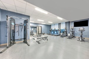 Un gimnasio con diversos equipos de ejercicio, incluyendo cintas de correr, elípticas y estaciones de levantamiento de pesas.