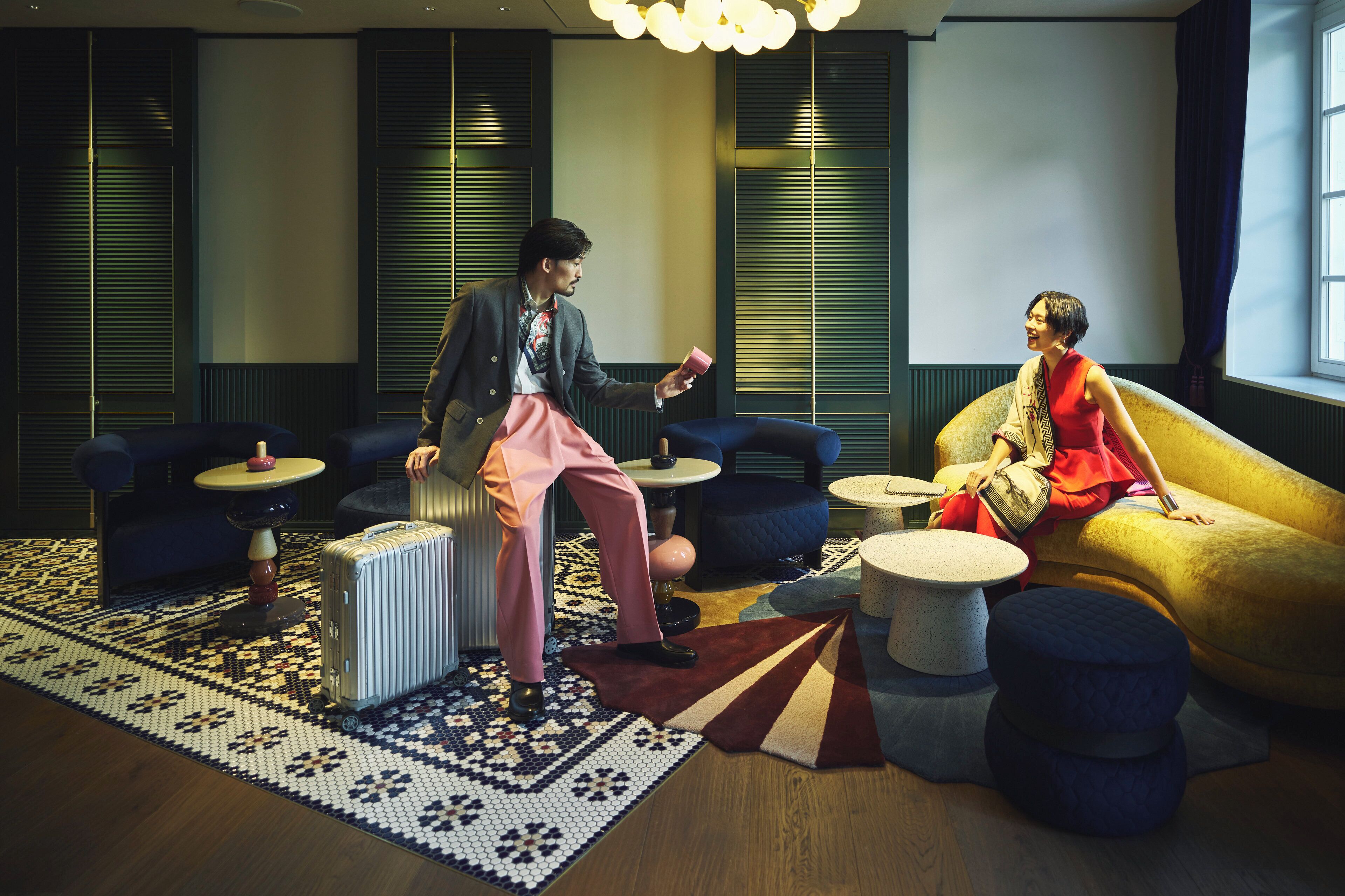 A modern hotel room with a large sofa, a small round table, and a patterned rug.