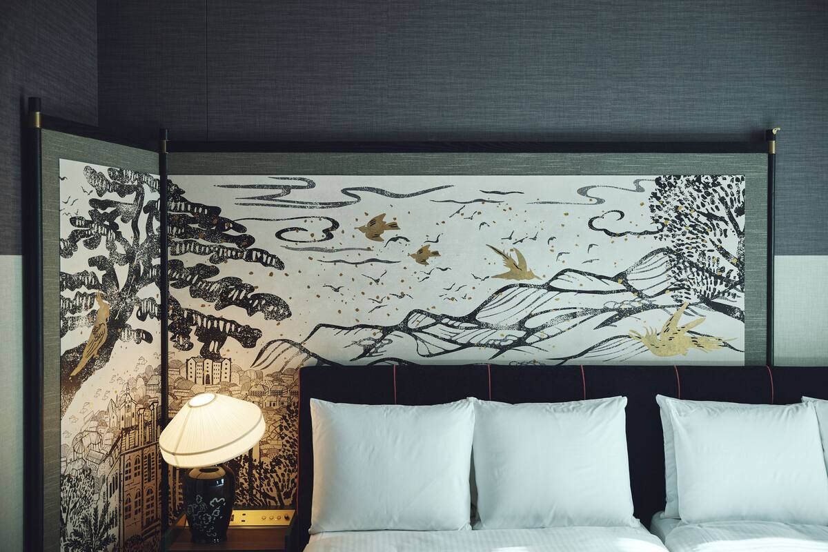 A room with a bed, a nightstand, and a wall with a mural.