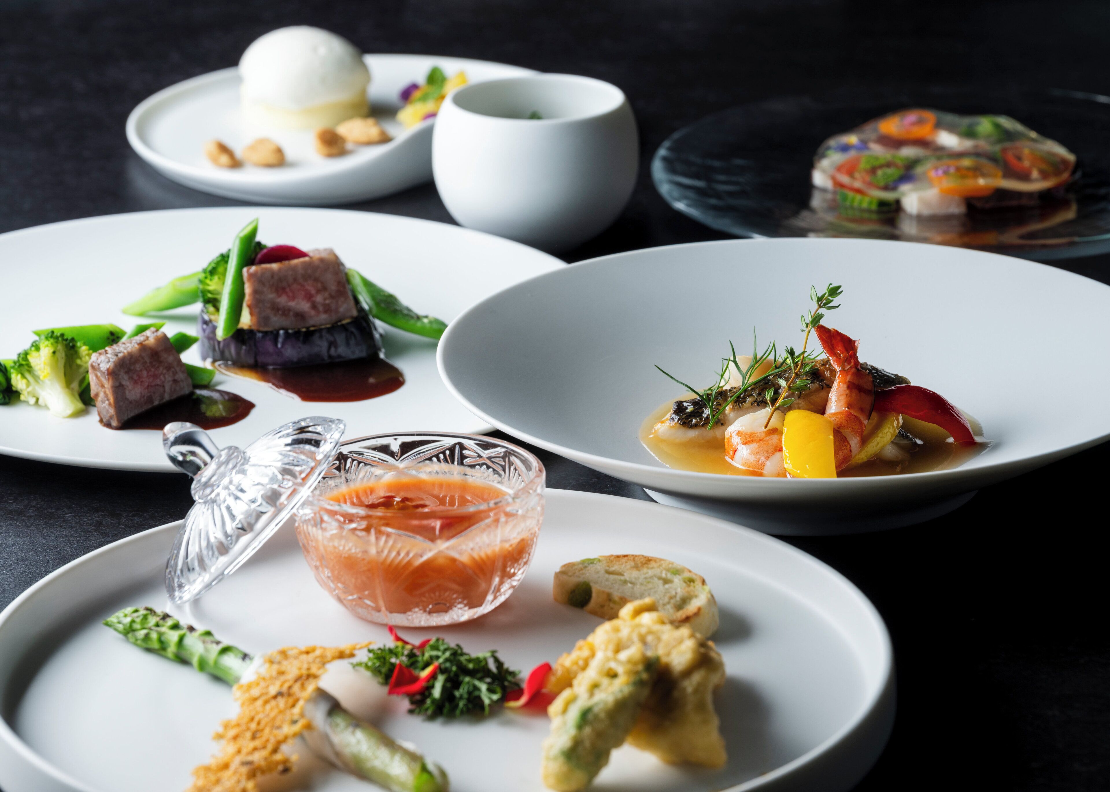 A variety of dishes on plates, including seafood, vegetables, and a dessert.