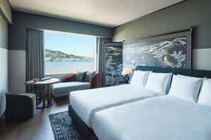 A hotel room with a large bed, a small table, a chair, and a view of the sea. - Hotel Indigo Nagasaki Glover Street by IHG (Nagasaki)