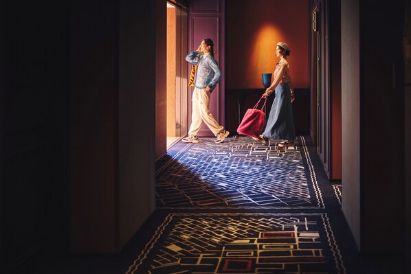 A hallway with patterned carpet and a door leading to a room.
