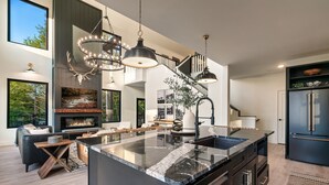 Une cuisine moderne dotée d’un grand îlot central, de meubles de rangement noirs et d’appareils électroménagers en acier inoxydable.
