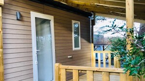 A wooden deck with a glass door and a small window, surrounded by a wooden fence. - Camping 3 étoiles - Piscine  - eehdba (Portel-des-Corbières)