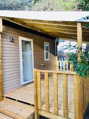 A wooden deck with a glass door and a small window, surrounded by a wooden fence.