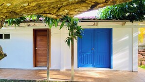 Un edificio con dos puertas, una marrón y otra azul, y un patio con baldosas.