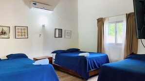 Habitación de hotel con dos camas, una ventana con cortinas y aire acondicionado instalado en la pared.