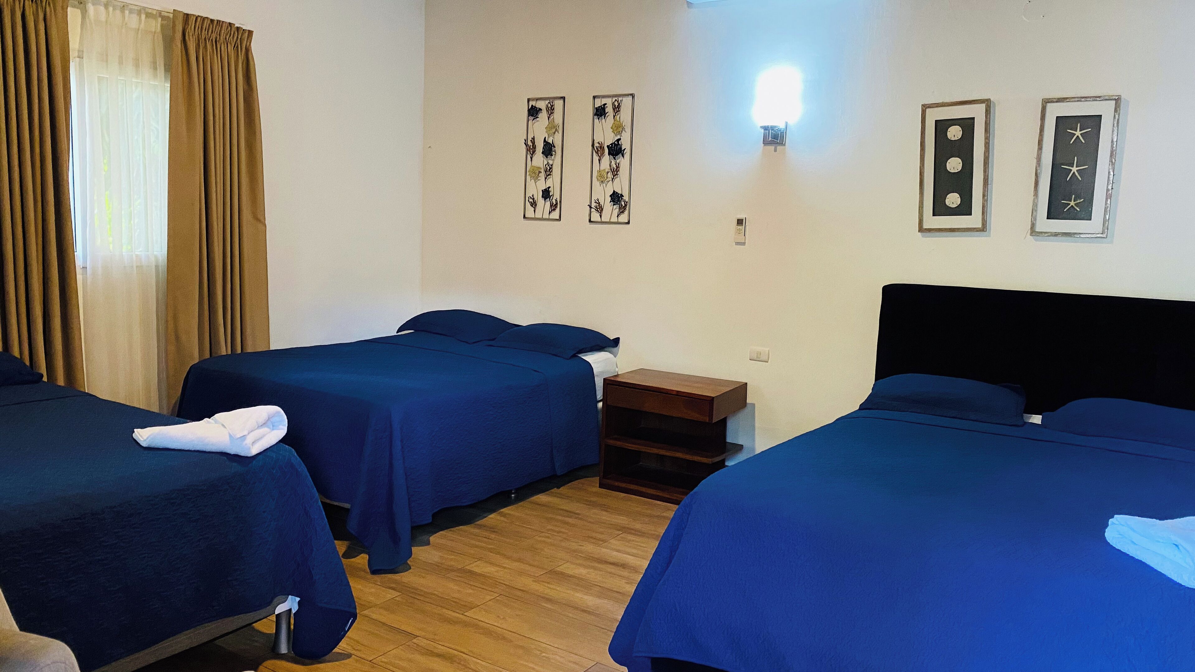 Een hotelkamer met twee bedden, een houten vloer en twee kunstwerken aan de muur.