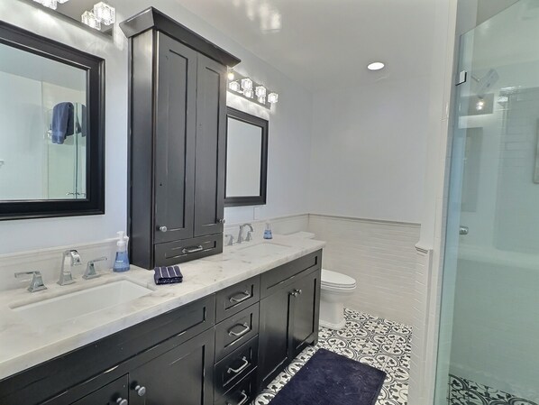 Un baño moderno con tocador doble, un espejo grande y cabina de ducha de vidrio.