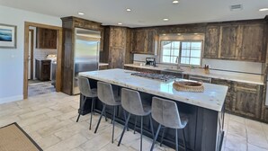 A modern kitchen with a large island, dark wooden cabinets, and a stainless steel refrigerator.