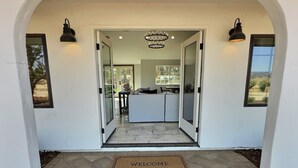 A modern entrance with a glass door leading to a living area with a sofa and a dining table.