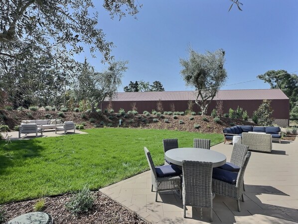 A patio area with outdoor furniture, a grassy lawn, and a building in the background.