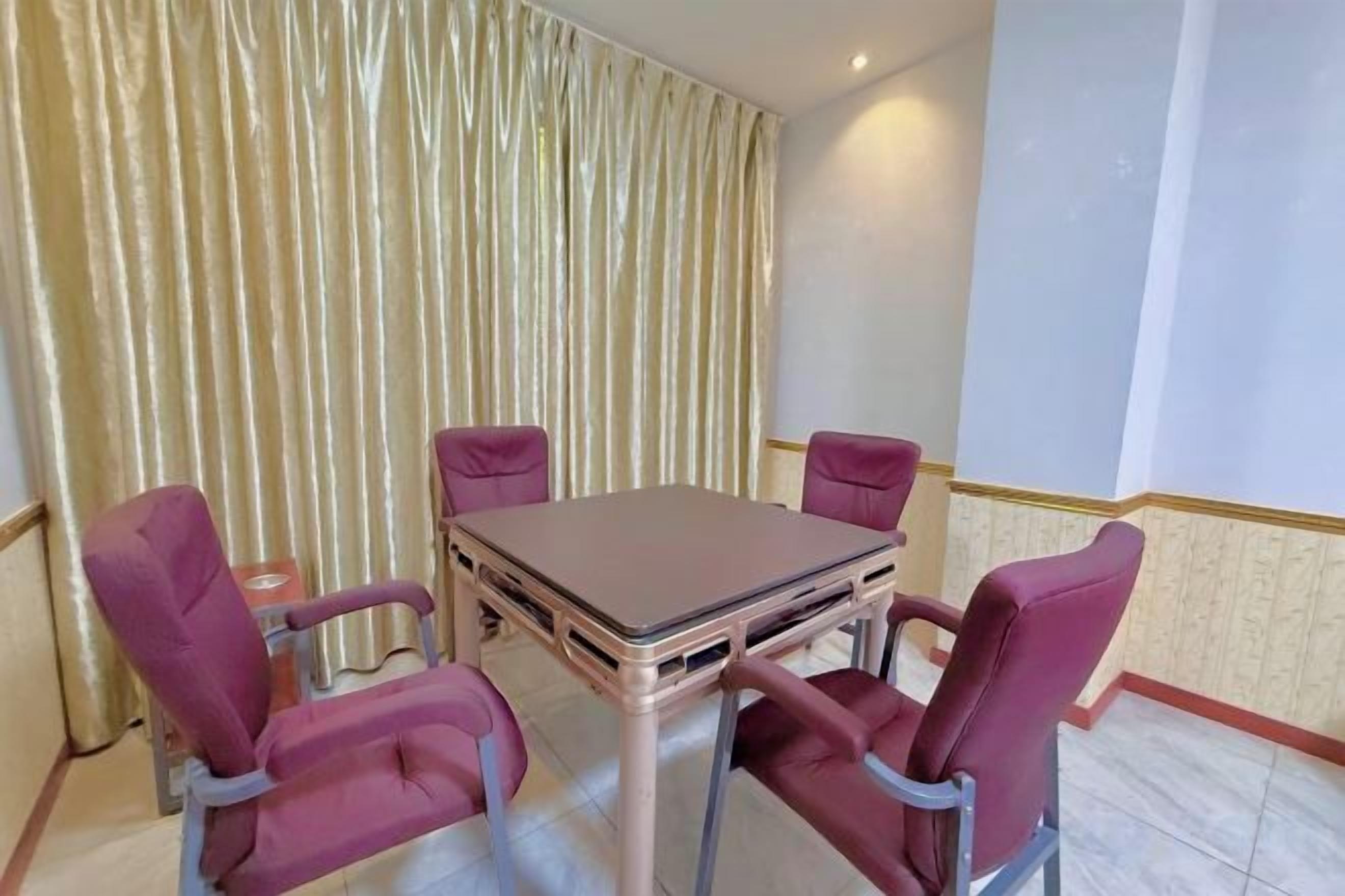 A dining area with a table and four chairs, a curtain, and a light-colored wall.