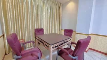 A dining area with a table and four chairs, a curtain, and a light-colored wall.