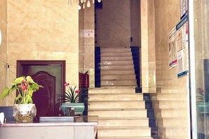 Un comptoir d’accueil avec une porte en bois, un escalier et des plantes en pot.