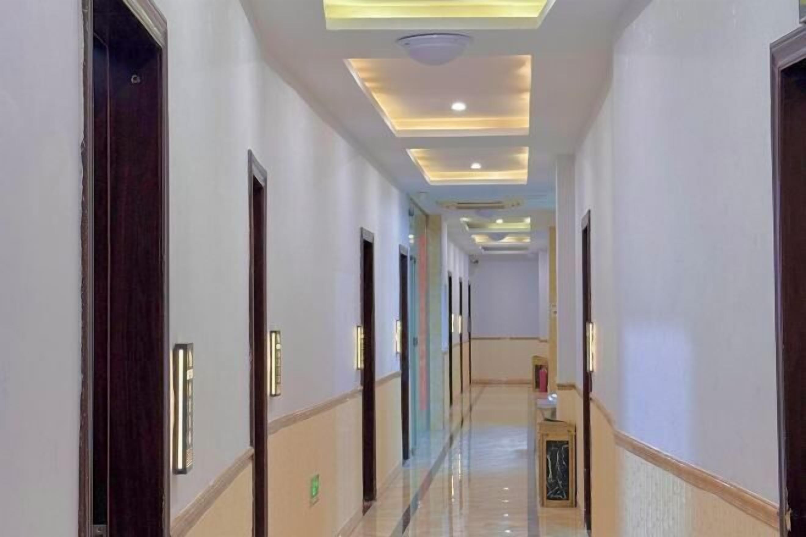 A hotel corridor with a modern design, featuring recessed lighting and a polished floor.